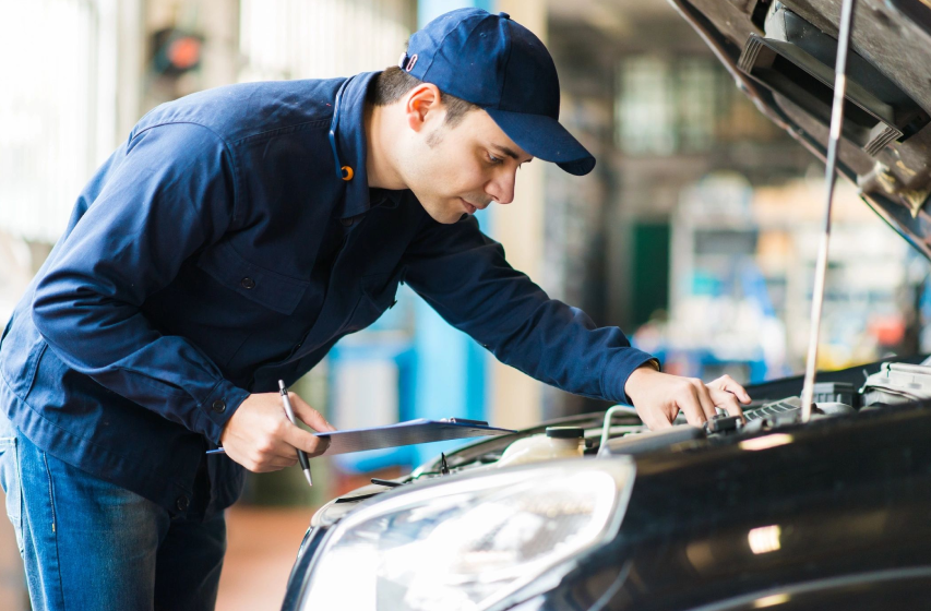 A man working on the hood of his car.