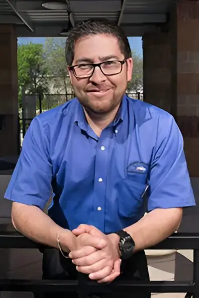 A man in blue shirt sitting at table.